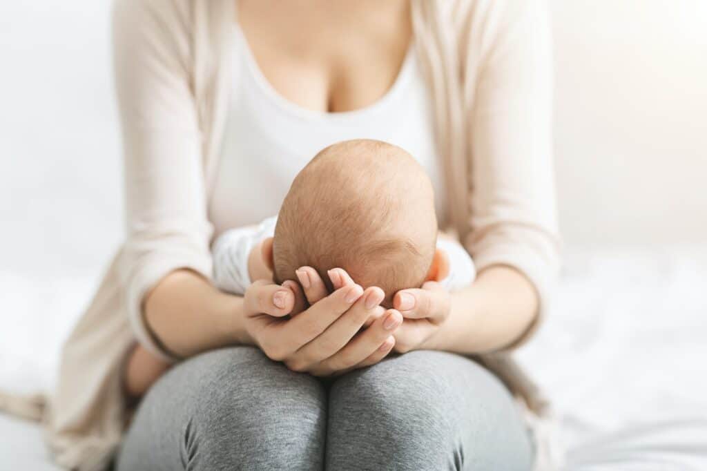 Mother holding head of her newborn baby in hands